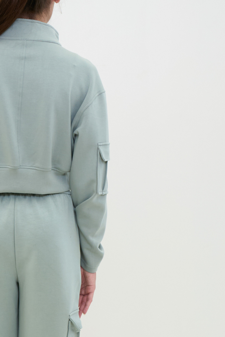 Person wearing a light green jacket and pants on a white background. ELOWEN sports set - Track suit zipper sweater and sweatpants Active wear front display. Women wearing a mint light green color tracksuit. back display