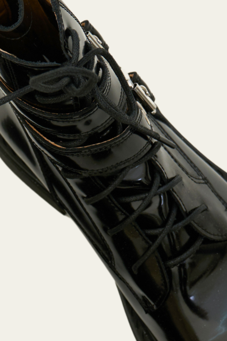 Close-up of a black leather boot with laces on a white background. Black high-top boots with zippers. Women’s Chelsea boots, timberland boots, military boots, heels boots, black boots with zippers. Leather boots. Close up top view.