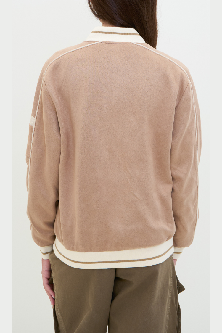 Person wearing a beige jacket with white stripes on a white background. Person wearing a beige bomber jacket with white trim. NAILA BASIC jacket in beige color with zipper. Unisex jacket. Back Image.