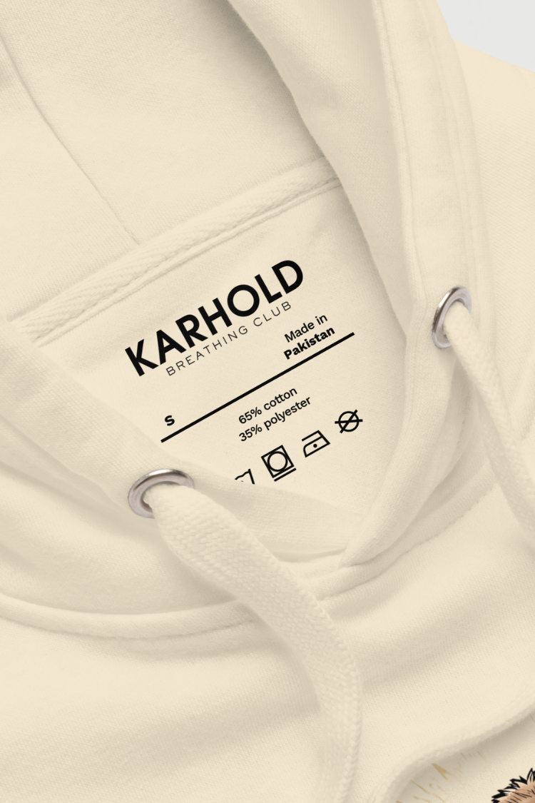 Close-up of a beige hoodie with Karhold branding and label details. Unisex hoodie Men’s hoodie Women’s hoodie Beige hoodie with a bear graphic and 'Just Breathe' text. 100% cotton. Close up image.