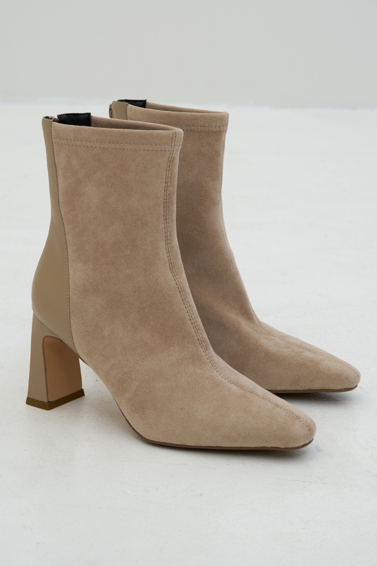 Pair of beige suede ankle boots. Woman wearing beige high heel ankle boots. Pointed boots in beige color. Fashion lifestyle shoes. High heels with pointed toes boots. Velvet boots.