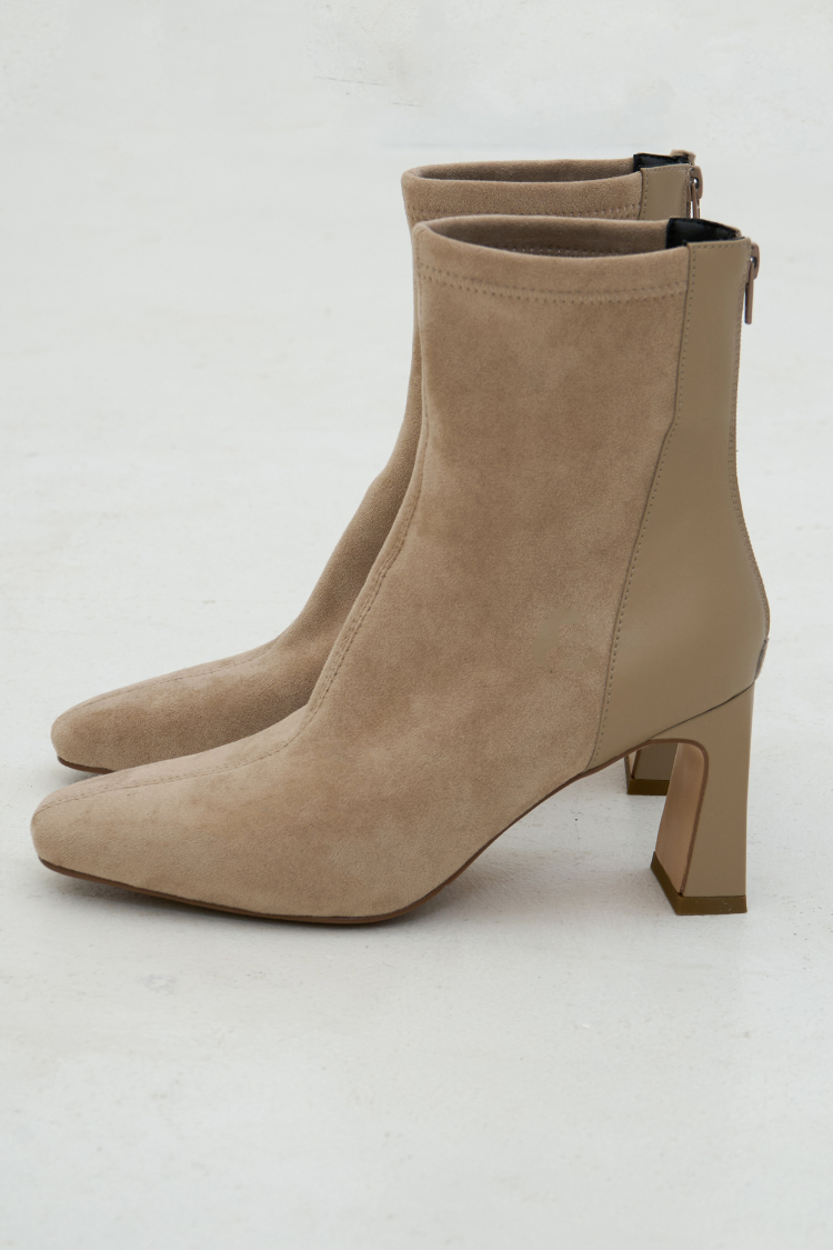 Pair of beige suede ankle boots. Woman wearing beige high heel ankle boots. Pointed boots in beige color. Fashion lifestyle shoes. High heels with pointed toes boots. Velvet boots. Side image.