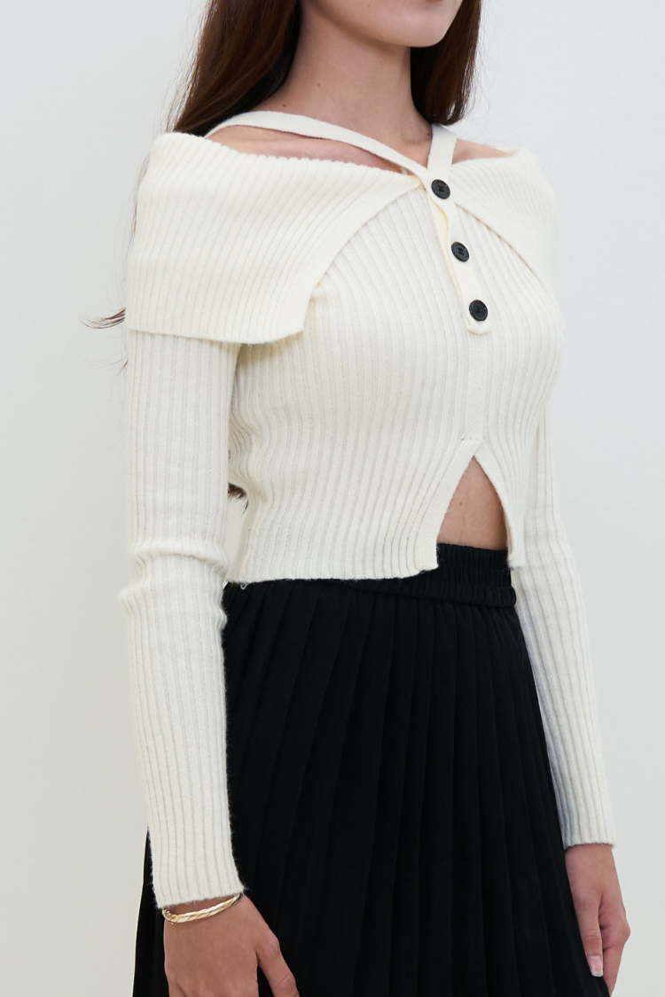 White ribbed sweater with cut-out design and black buttons worn by a women.