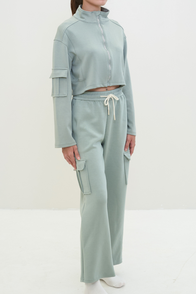 Women wearing a light green tracksuit  (Zipper sweater and sweat pants) Wide legged pants mint color. Track suit zipper sweater and sweatpants Active wear front display. Women wearing a mint light green color tracksuit.