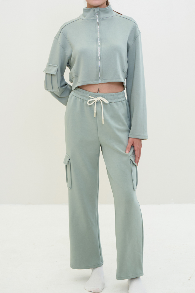 Person wearing a light green tracksuit on a white background.ELOWEN sports set 6 - Track suit zipper sweater and sweatpants Active wear front display. Women wearing a mint light green color tracksuit. full body display. 